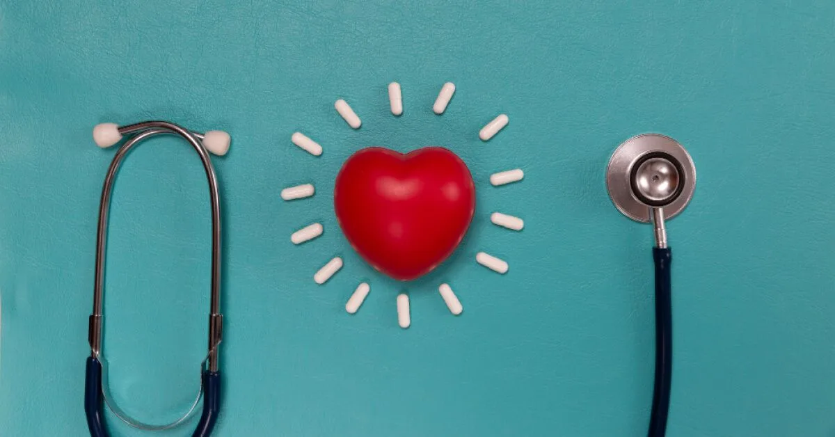 Red heart with white pills and a stethoscope around it