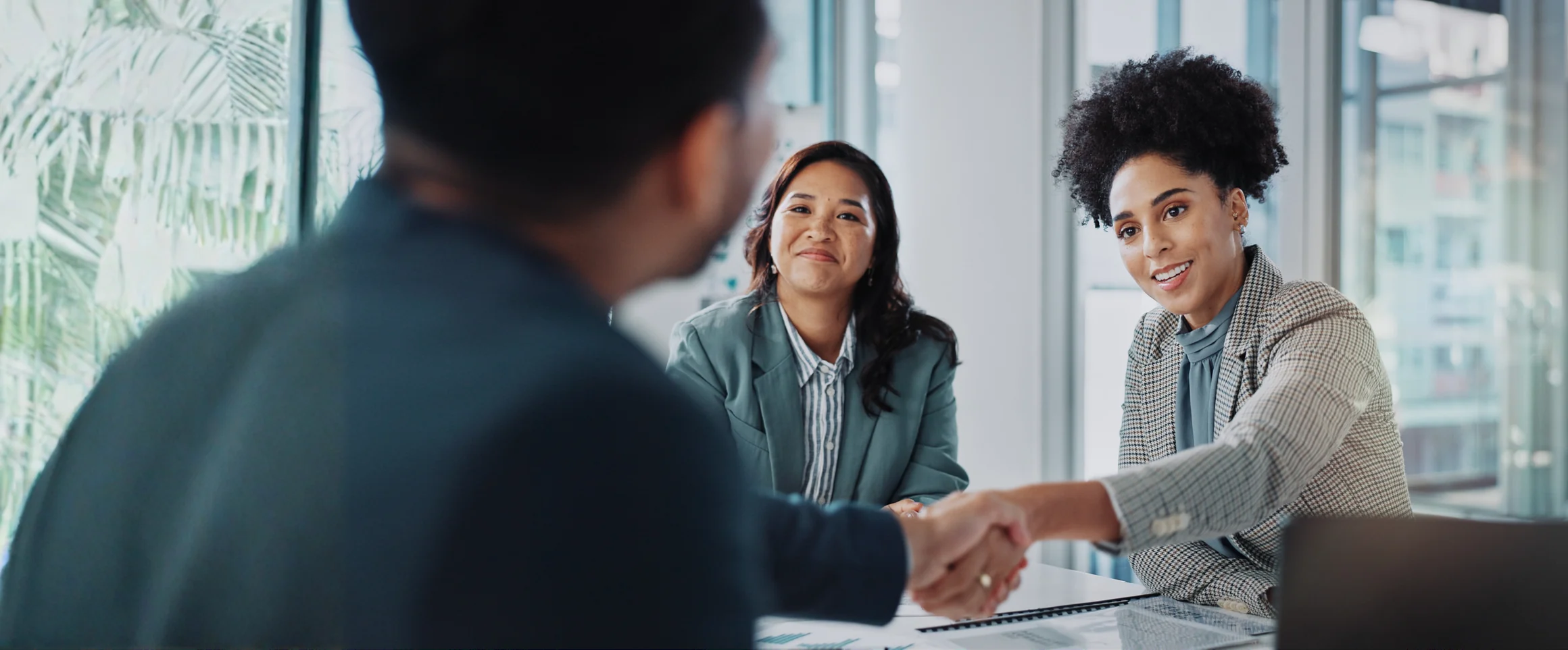 A hiring panel shaking hands with a candidate across a meeting table