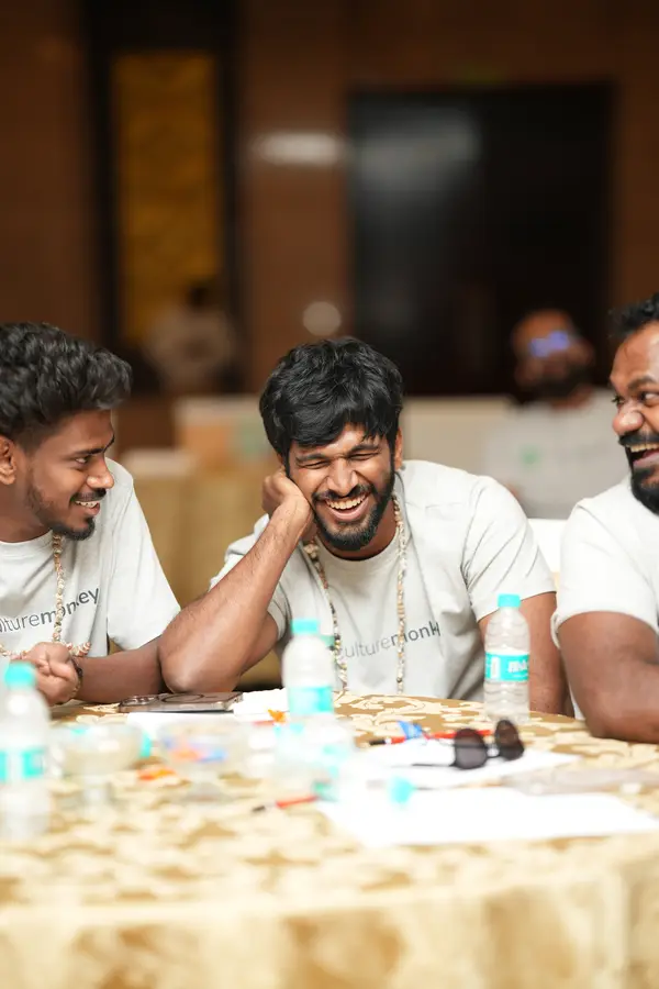 Three team members laughing hard together at a table